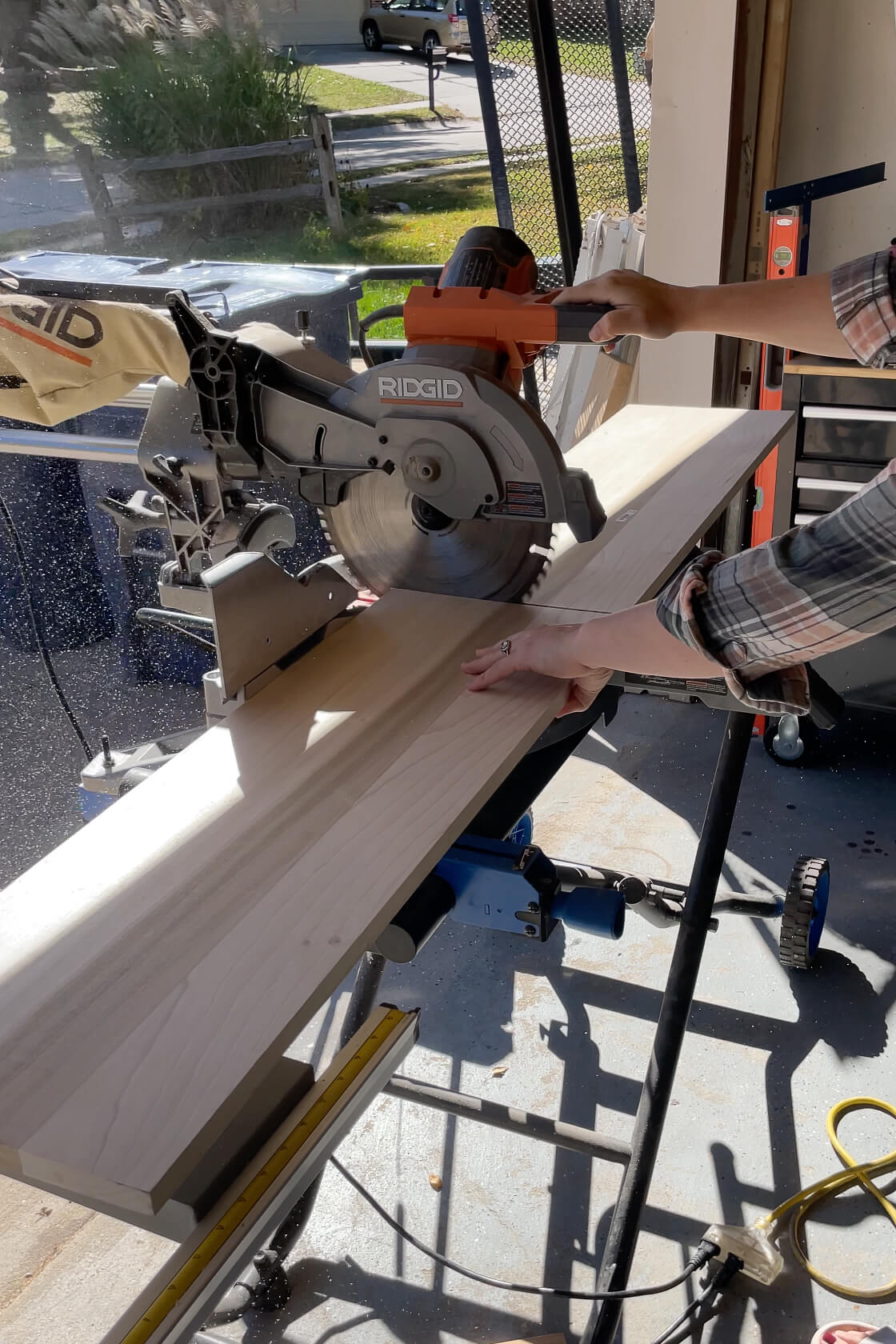 Using a miter saw to cut down shelf boards for a DIY floating bathroom shelf.